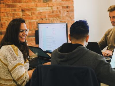 Three people sat around a desk, one smiling, all at work